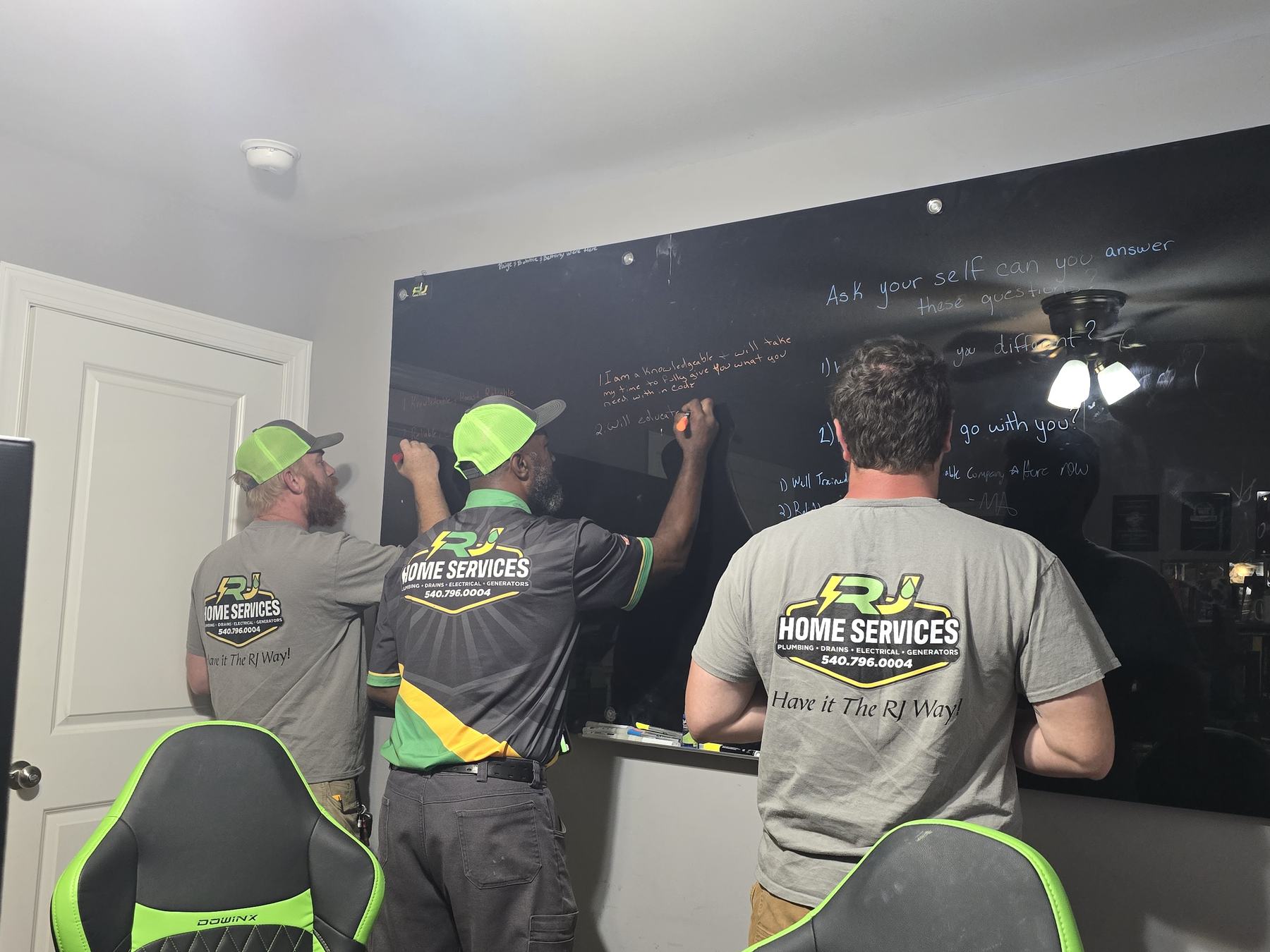 Three RJ techs in branded shirts writing on a whiteboard