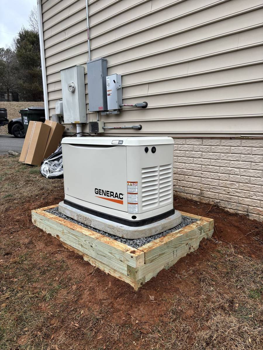 Generac unit on a timber-framed gravel pad below the transfer switch