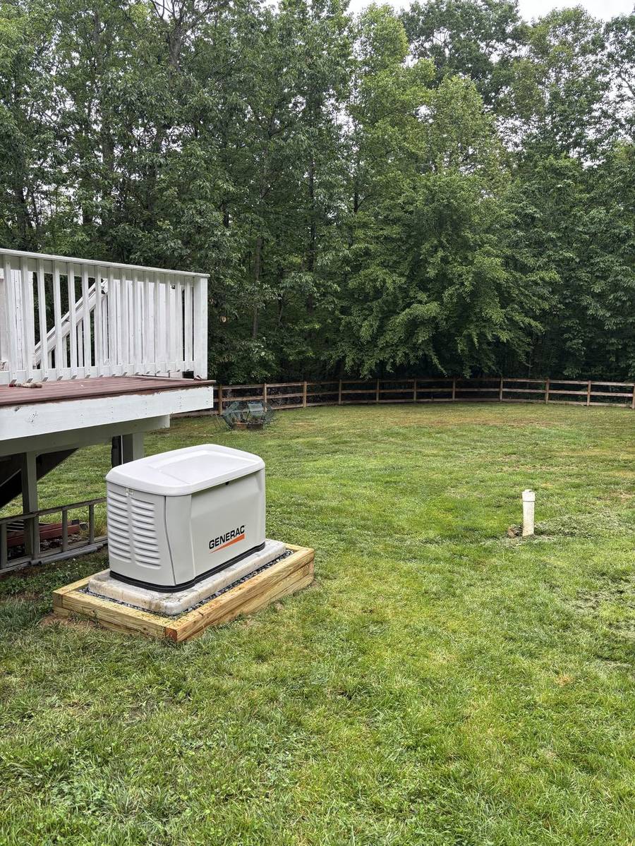 Generac standby generator in a back yard beside a deck